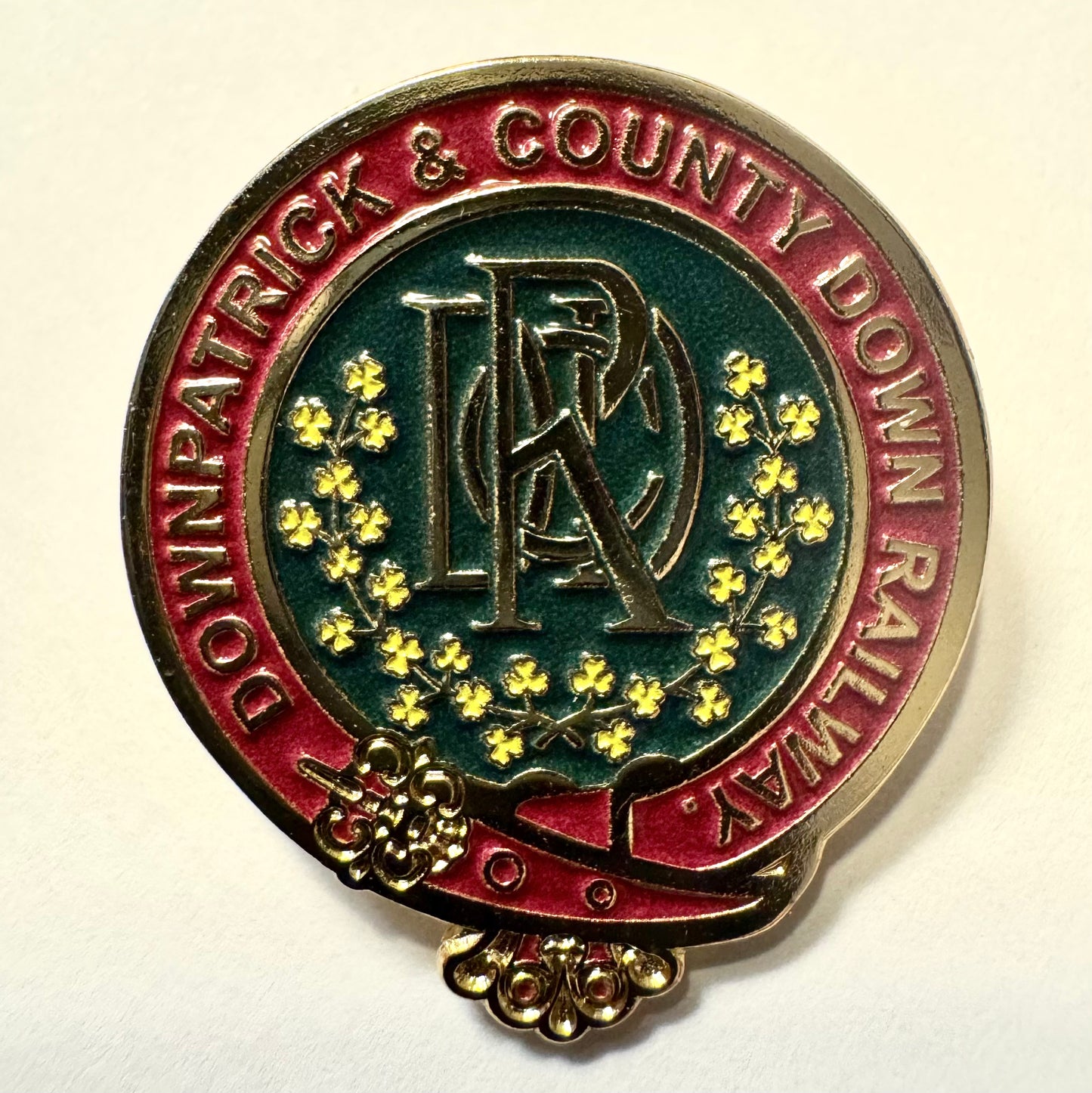 Metal badge with 'Downpatrick & County Down Railway' text and emblem on a white background
